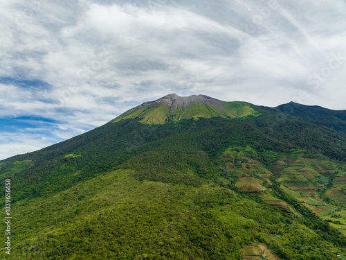 Top view of farmland with plantings against a background of mountains and blue sky. Kanlaon volcano. Negros, Philippines