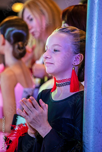 happy girl in a dance dress claps her hands, supporting the participants at the tournament.