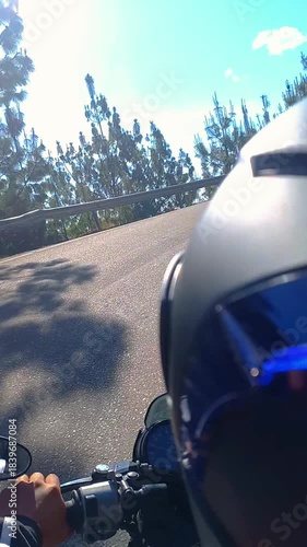 Motorcyclist riding fast on a motorcycle on a road in a rural setting, forests, and mountains 