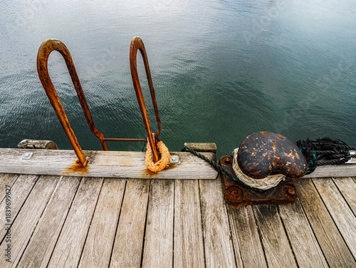Rusted Ladder And Bollard On Pier Edge