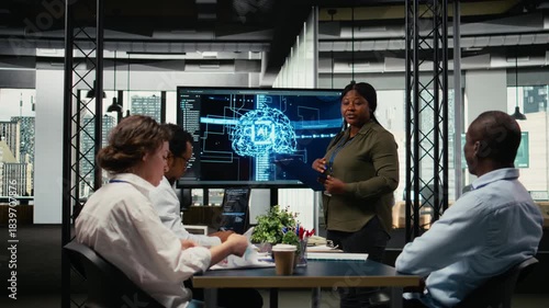 Investors meet in startup office to hear technology presentation from experienced computer scientist. African american woman and businessmen in tech agency boardroom participating in pitch, camera A