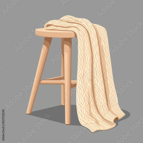 Cozy knitted blanket draped over a wooden stool in a minimalist setting