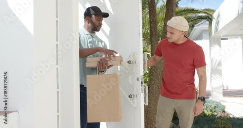 Customer opening door and exchanging paper bag and pizza boxes with delivery driver, copy space