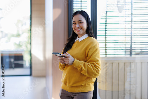A woman wearing a yellow shirt is using her phone in the office. Free Download A woman wearing a yellow shirt is using her phone in the office. - GFXLoad