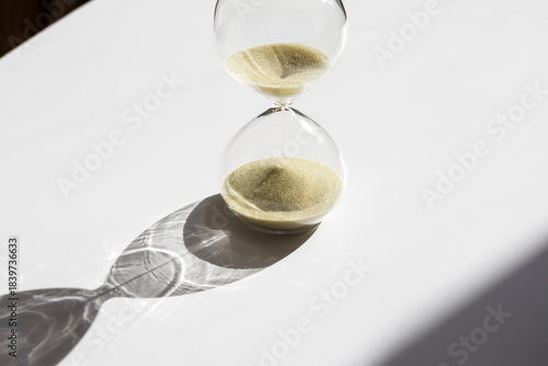 Hourglass with golden sand illuminated by the sun. Concept of aging and time. Selective focus and space for text