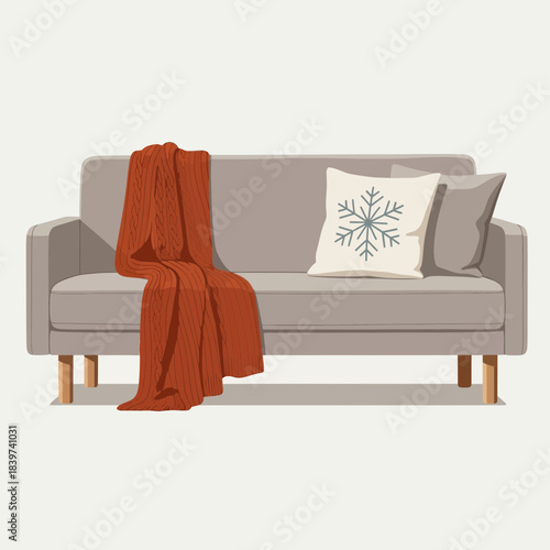 Cozy living room couch with winter-themed pillow and warm throw blanket for a comfortable indoor