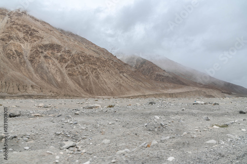 A dry rocky valley in Ladakh with barren mountains, rugged terrain, and a dried river trail under clear sky. Minimal, raw landscape perfect for travel, geography, adventure and Himalayan themes.