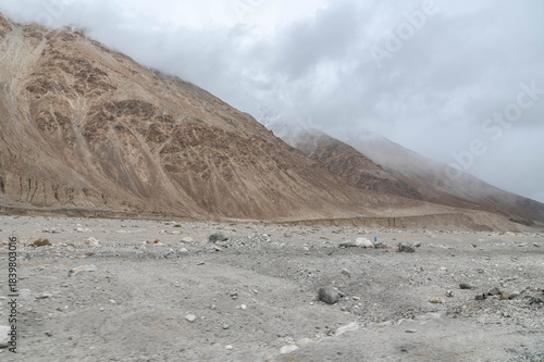 A dry rocky valley in Ladakh with barren mountains, rugged terrain, and a dried river trail under clear sky. Minimal, raw landscape perfect for travel, geography, adventure and Himalayan themes.