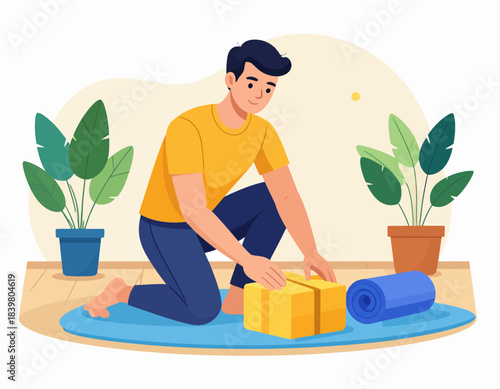 A man in a yellow shirt kneeling on a blue mat, preparing a yellow box indoors with plants.