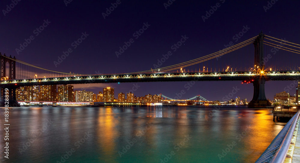 Fototapeta premium Night view of Manhattan Bridge with city lights reflecting on water