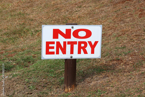 No Entry sign mounted on a wooden post in a grassy area