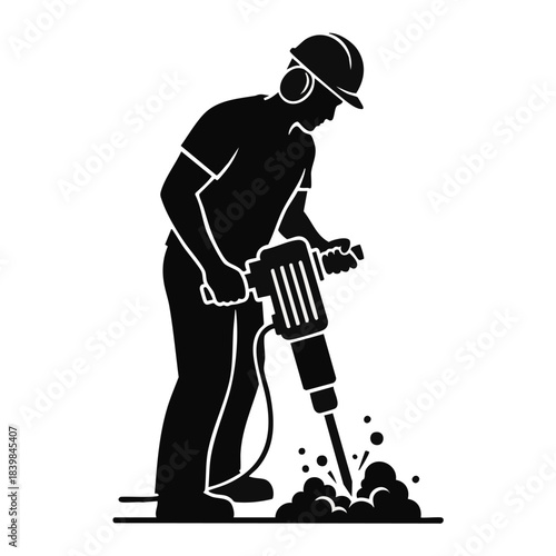 Silhouette of a construction worker using a jackhammer to break concrete.