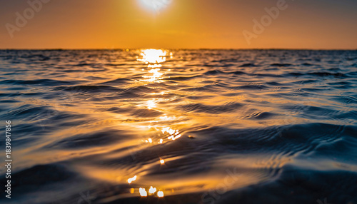Sunlight reflects on calm ocean waves during golden hour sunset