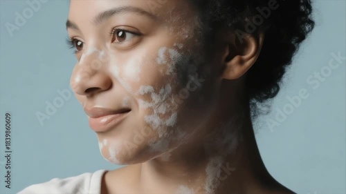 Portrait of a woman's face with white facial treatment against a light blue backdrop