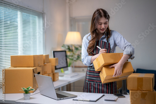 Online seller writing address on cardboard box in warehouse