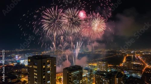 Vibrant Pink and White Fireworks Explode Over a City Skyline at Night with Tall Buildings