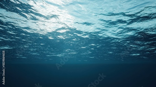 Fototapeta Naklejka Na Ścianę i Meble -  Deep blue ocean water surface viewed from below with bright sunlight filtering through the rippling waves