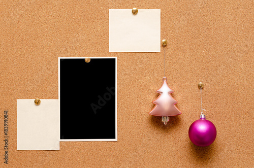 Empty photos and Christmas tree toys are pinned on a cork board. Copy space