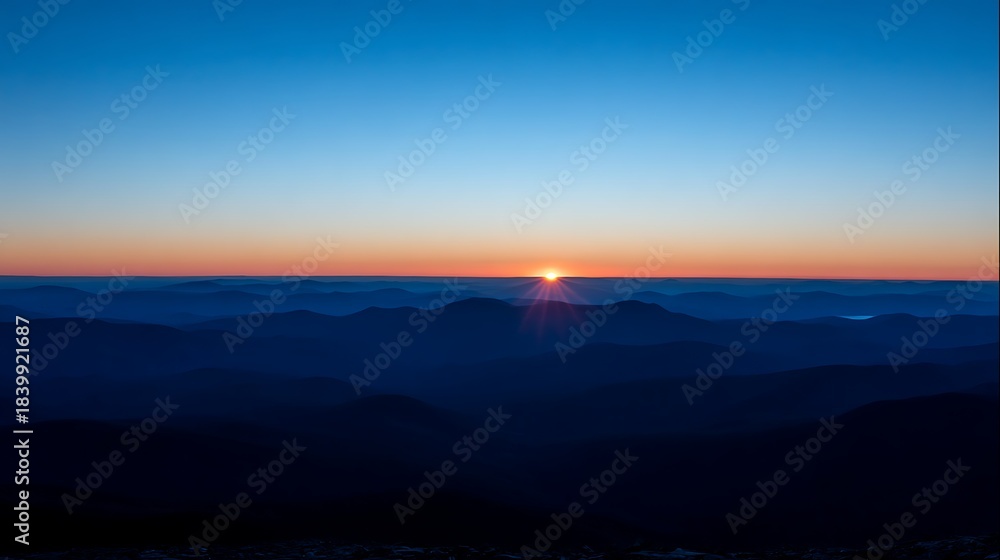 Fototapeta premium A vibrant sunrise emerges, casting light over layered mountain ranges against a gradient sky