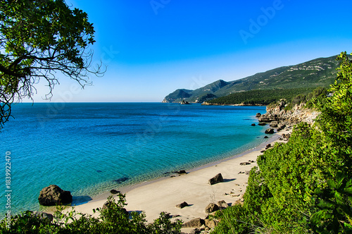 Obraz na płótnie Serene coastal landscape with clear turquoise waters and lush green hills under