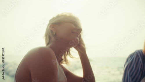 Happy woman with blonde hair smiling while enjoying the warm sunset and ocean breeze on a boat. Her hair blows in the wind, feeling the freedom of the sea.