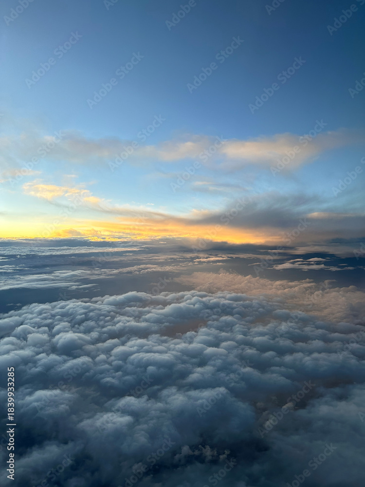 Fototapeta premium Dramatic cloudscape during sunrise from the airplane's window