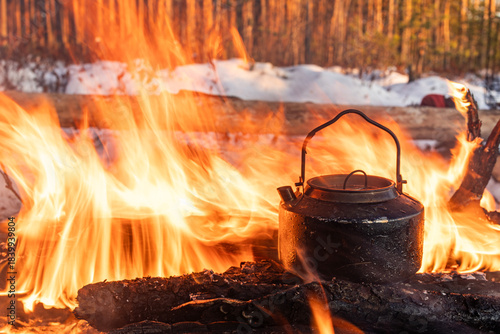 A kettle boils on a camp fire in the forest. Forest fire on a hike.