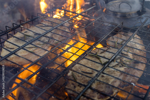 Grilling steaks over a campfire in the forest.