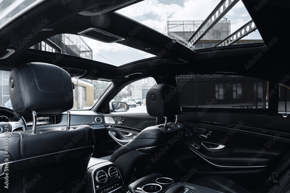Fototapeta premium Luxury car interior showcasing a panoramic sunroof in an urban setting