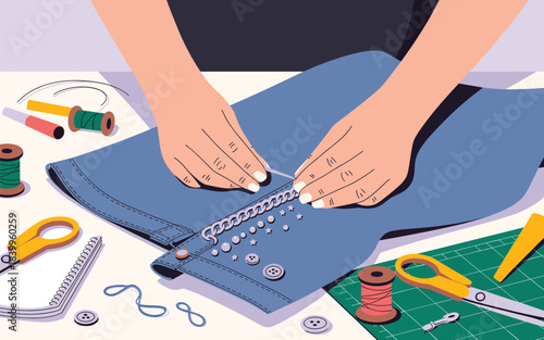 A person is sewing buttons onto a blue fabric garment on a table surrounded by sewing tools and supplies