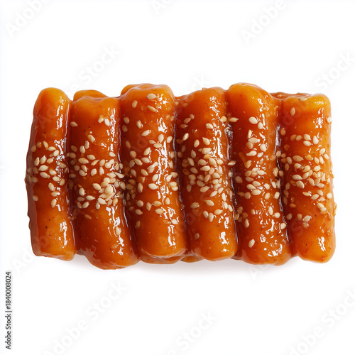 Tteokbokki lined in precise rows, thick sauce glaze reflective, sesame only on one side