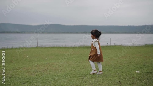 slow motion of toddler girl walking on a grass field near the river
