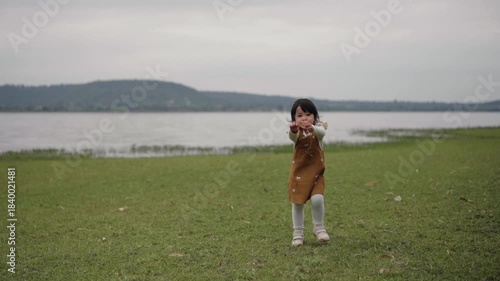 slow motion of toddler girl walking on a grass field near the river