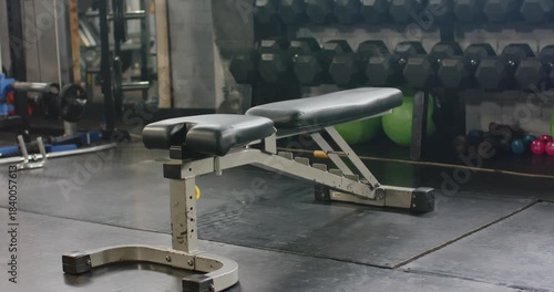 Bench is holding position while camera is panning right to reveal dumbbells and green balls