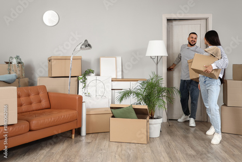 Fotografija Young couple with boxes entering through door into rented apartment on moving da