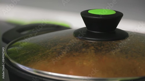 Close up of boiling food under glass lid with condensation, suggesting cooking process