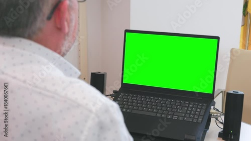 Over the shoulder view of a man working on a laptop with replaceable screen