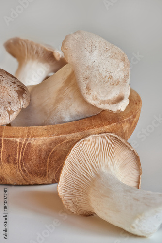 Closeup shot of a group of fresh mushrooms  lying in a wooden texture bowl on a white table