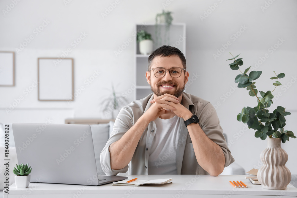 Fototapeta premium Young man with laptop at desk in office