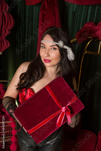A young beautiful woman dressed in gloves stands in a hotel interior and holds a gift