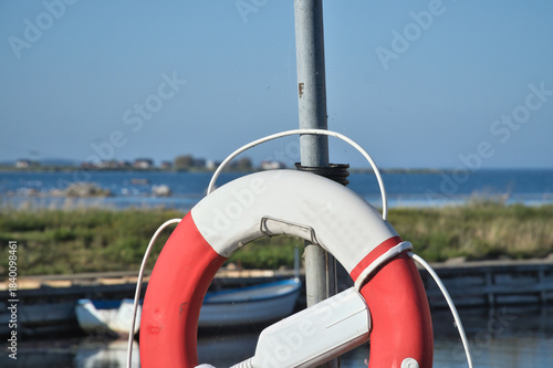 Lifebuoy at the small harbor with a view of the water and coastal landscape