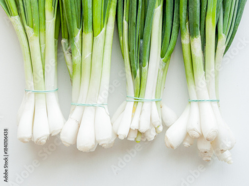 Fresh green leek onion on wooden background, top view bunch of greens on the table.