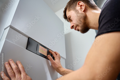 Fotografía Man adjusting control panel on heat pump inside modern home during installation