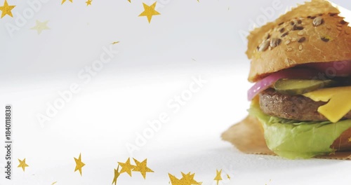 Falling gold stars starting bun unveiling while camera shifting to show wrapped burger on white set