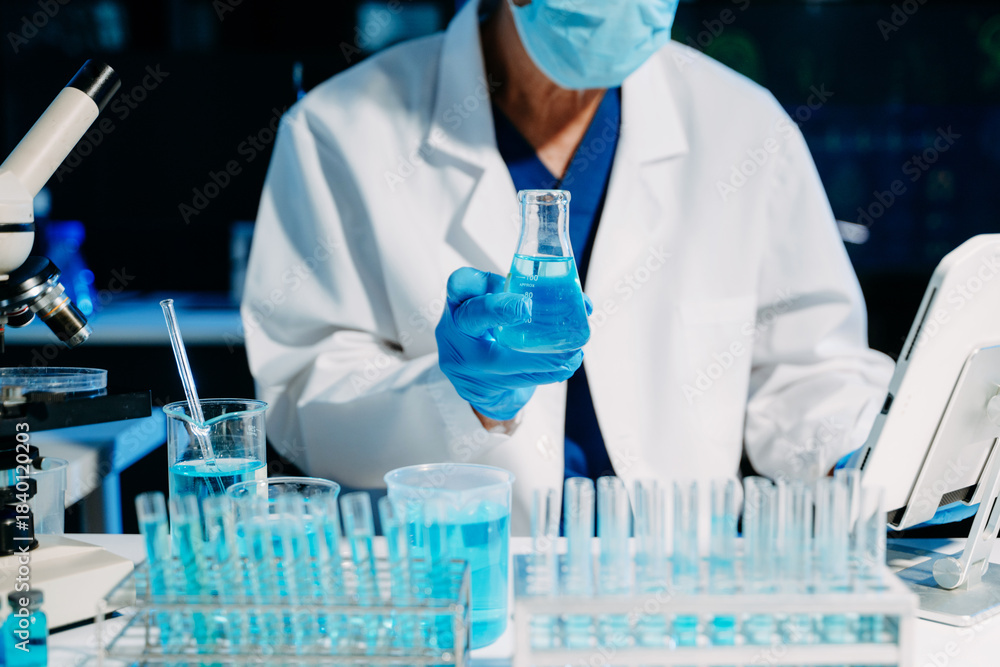 Fototapeta premium scientists in lab coats conducting research, handling glassware, and working with chemicals in a modern, high tech laboratory.