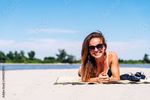Beautiful relaxed woman sunbathing on tropical sandy beach during summer vacation.
