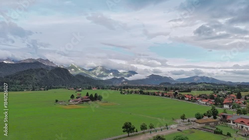 Aerial view from drone flying over village houses towards the castle on hill above summer field near Neuschwanstein Castle in Germany, Europe. High quality footage in 4k format