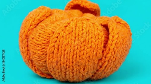 Knitted tangerine spinning gently, partially peeled against a vibrant background