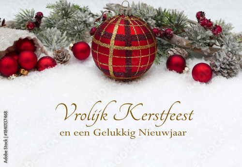 Kerstkaart: Kerstgroeten met kerstboomversieringen en dennentakken in de sneeuw. Vrolijk kerstfeest en een gelukkig nieuwjaar.