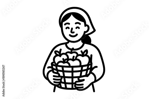 Smiling female agricultural worker carrying a wicker basket filled with ripe apples